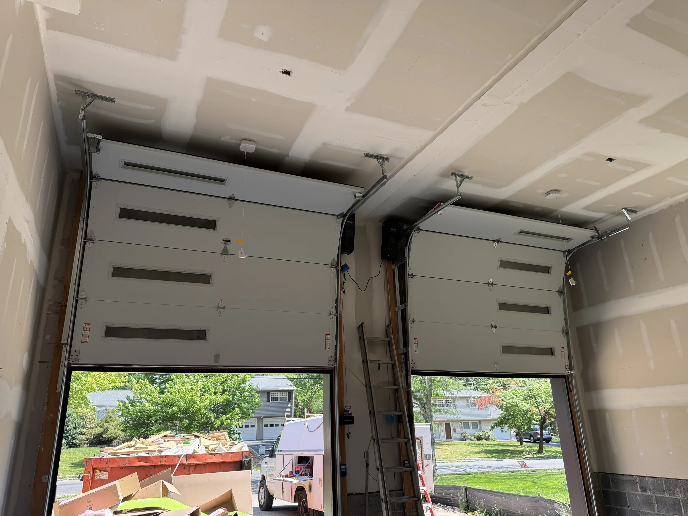 Interior residential garage view showing garage door tracks, hinges, opener rails, and installed hardware.